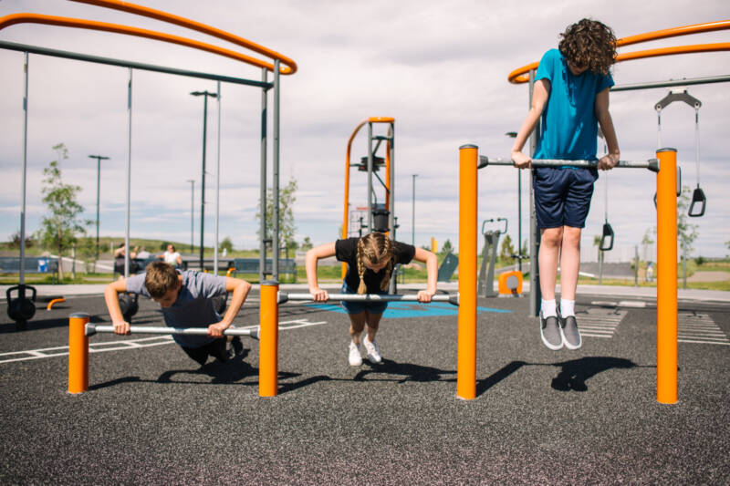 Three kids working out on the three level push up bars